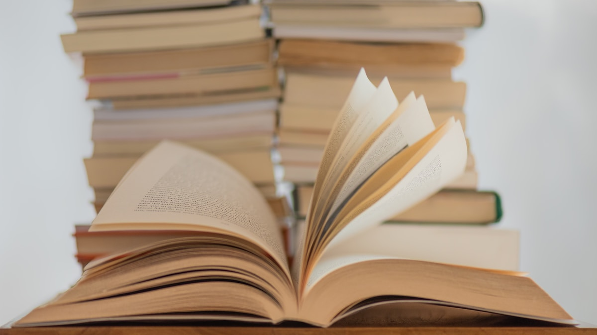 Book is open with pages falling in front of a stack of other books