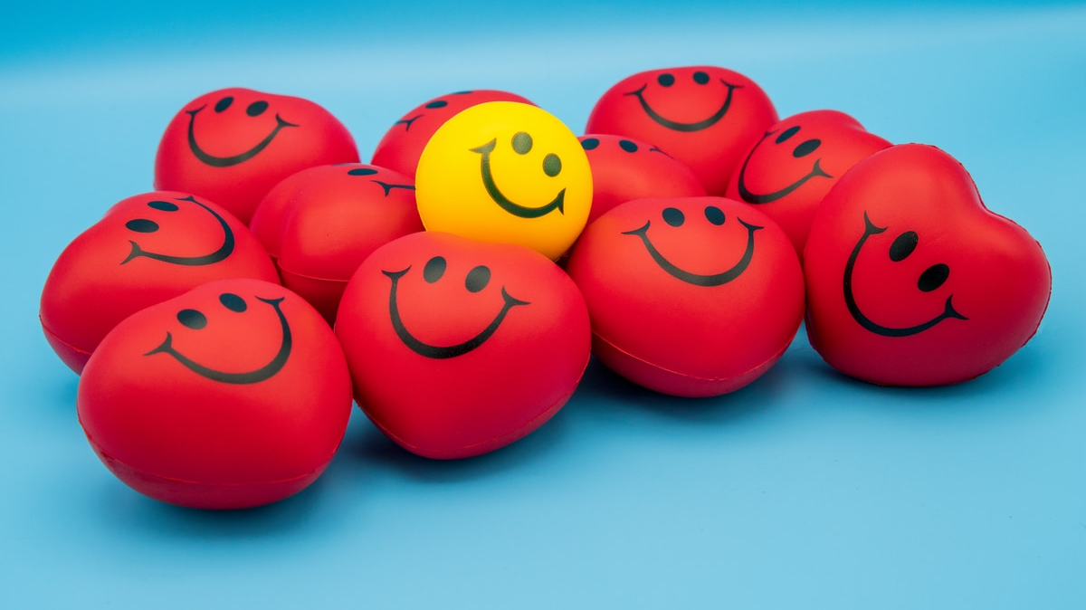 Heart shaped red balls with smiley faces are the bed for a yellow smiling face ball