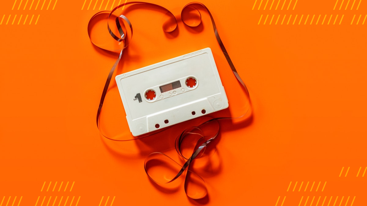 Cassette tape shows recording tape torn out on orange background