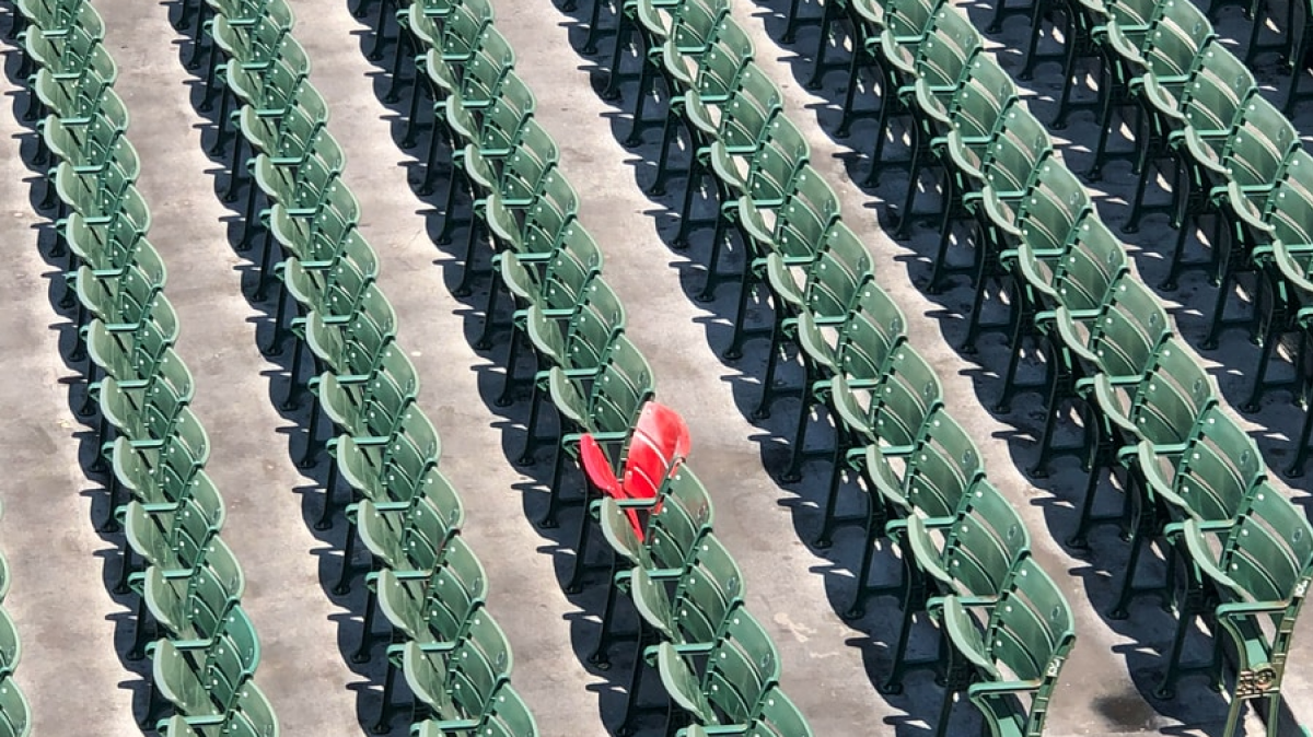 Red chair stands out in sea of green chairs in stadium seating